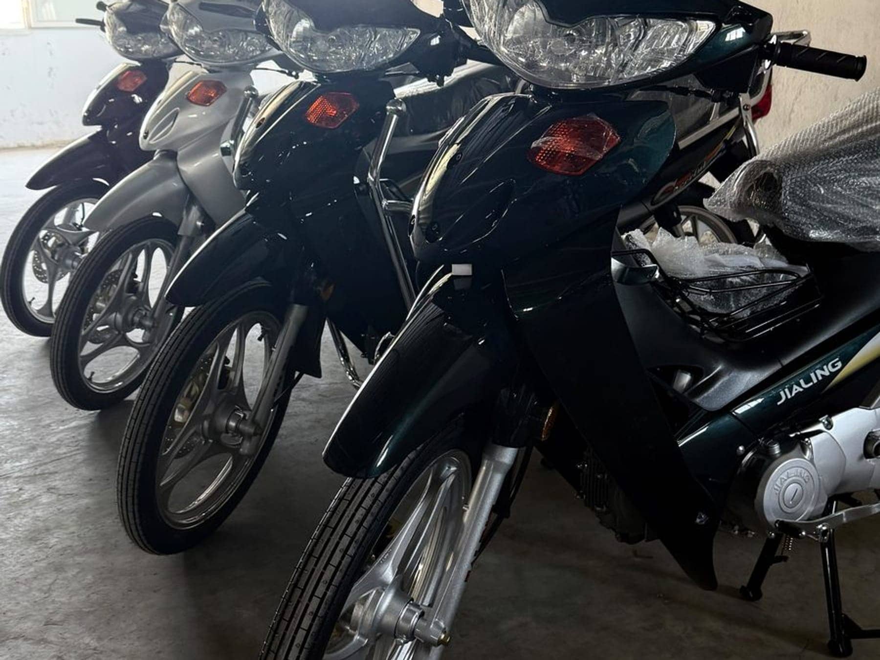 Row of new Jialing motorcycles in factory wrap in the official importer's depot in Ben Arous