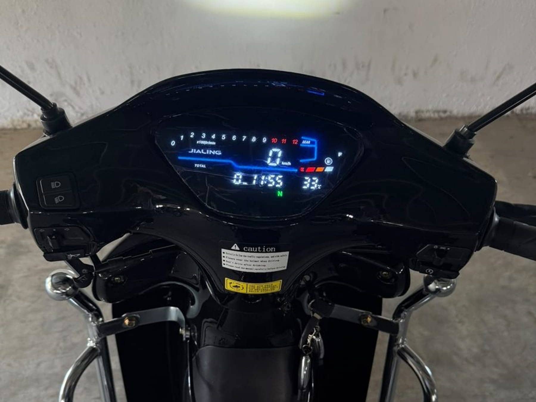 Lit digital dashboard of a new Jialing motorcycle, odometer at 0.1 km, in the Jialing Tunisia depot
